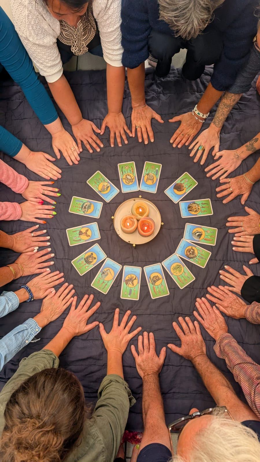 Les mains des participants posées en cercle autour de cartes et de bougies